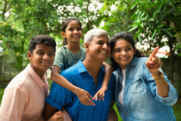 Indian Asian family of four, parents in their forties with two children, in outdoor pointing happily