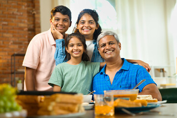 Indian Asian family of four enjoying quality time together around the dining table at home