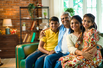 Cheerful Indian Asian family poses for a close-up photo while sitting on the sofa