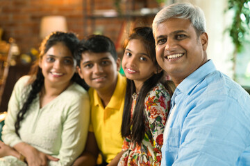 Cheerful Indian Asian family poses for a close-up photo while sitting on the sofa