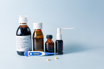 Seasonal diseases. Cold, runny nose, cough Medicines, spray and syrup, thermometer, pills, capsules on pastel background