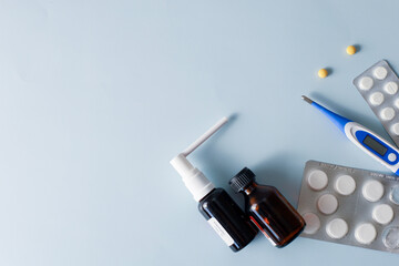 Seasonal diseases. Cold, runny nose, cough Medicines, spray and syrup, thermometer, pills, capsules on pastel background