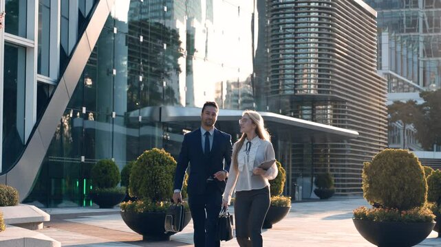 Two Confident Business People Walking Out of Office Building, Talking and Spending Time Together Outside. Business Partners Discussing Work Issues On the Go - slow motion