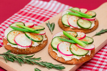 Light Breakfast or Diet Eating - Crispy Cracker Sandwich with Cream Cheese, Fresh Cucumber, Green Onions and Radish on Wooden Cooking Board on Magenta Background