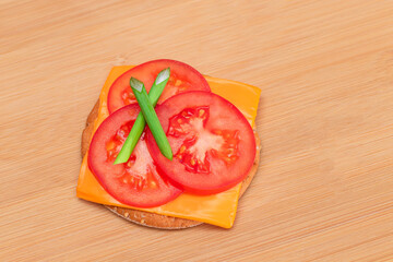 Crispy Cracker Sandwich with Tomato, Cheese and Green Onions on Cutting Board. Easy Breakfast. Diet Food. Quick and Healthy Sandwiches. Crispbread with Tasty Filling. Healthy Dietary Snack