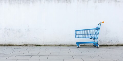 blue shopping cart positioned against a white concrete wall