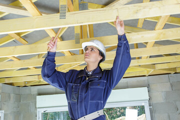 female builder using hammer to work on roof timbers