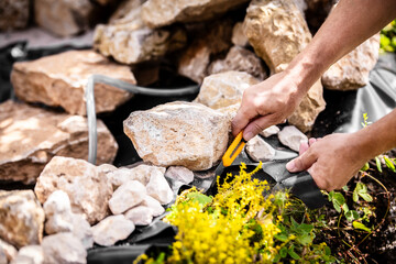 man cuts a special foil for a garden pond