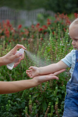 mother applies an aerosol insect spray to the child's body. Selective focus