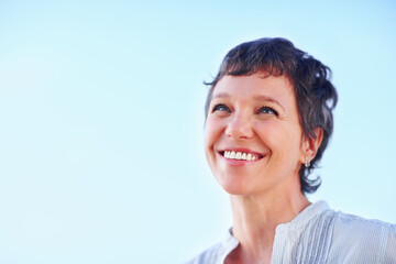 Mature, woman and thinking smile on blue sky for holiday, travel or vacation in retirement. Confidence, mockup and space with happy tourist person outdoor in summer for peace, sightseeing or wellness