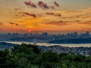 TURKEY, ISTANBUL, JUNE 2021. A breathtaking sunset over Istanbul, captured from a hill. The sky is painted in vibrant hues, highlighting the bridge and glistening bay below, blending history