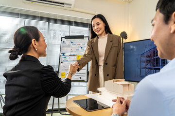 Asian Architects and department manager teamwork shaking hands after success presentation 3D architectural displayed model, negotiation and deal in meeting or casual, Greeting