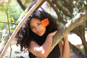 portrait of a beautiful young Latin woman with large, dark eyes and curly hair. The girl wears an...