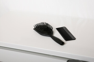 Used hair brush and comb full of hair on white table, head skin hygiene concept