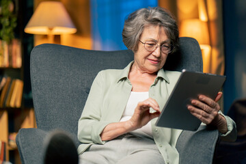 close up warm light living room with library big blue armchair elderly woman sitting watching a...
