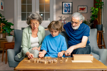 a bright living room with sofa grandpa and grandma sitting with grandson on table collecting words from cubes hand motor skills mind training