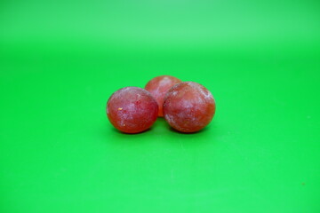 3 grapes isolated on green background. Fresh purple grapes.