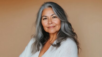 Portrait of a pleased Native American woman in her 40s with gray hair and a warm smile wearing a cozy white sweater