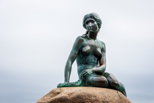 Copenhagen, Denmark - July 16, 2024: The Little Mermaid is a bronze statue by Edvard Eriksen depicting the character in the 1837 fairy tale by H.C. Andersen, displayed since 1913 on a rock by the sea.