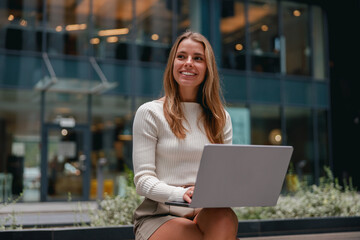 A cheerful woman is working diligently on her laptop in a modern office setting today
