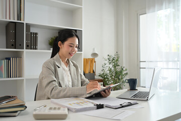 Professional businesswoman in trendy suit working with digital tablet at workplace