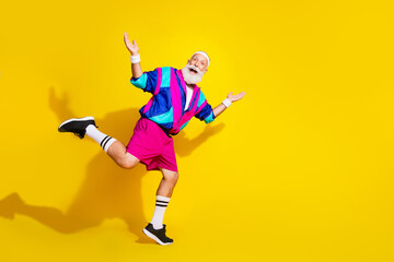 Full length photo of handsome good mood senior guy oldschool sportswear enjoying running emtpy space isolated yellow color background