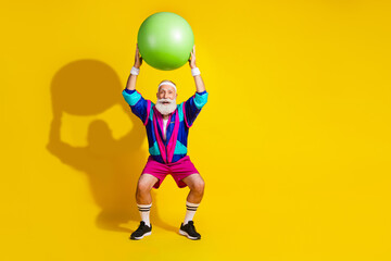 Full length photo of handsome good mood senior guy oldschool sportswear rising fit ball emtpy space isolated yellow color background