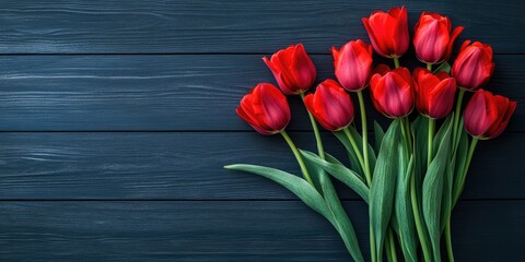 A cluster of red tulips arranged on a dark wooden surface. Mockup, space for text.