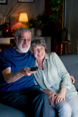 close up a bright living room with sofa grandma and grandpa watching tv switching channels leisure of elderly people happy couple
