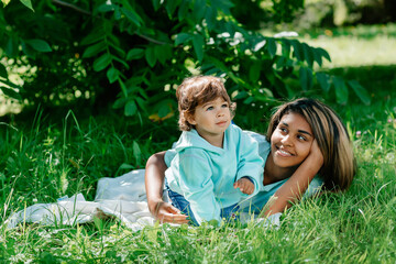 Fototapeta premium African American mother and son having fun in the park. Black family having fun outdoors, mom playing with his cute child