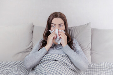 Concept of disease, home treatment. A woman caught a cold, blows her nose in a napkin