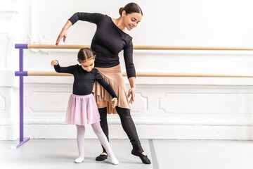Graceful child and teacher dancing together in studio