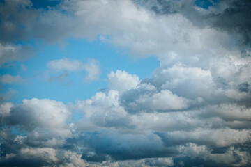 Dramatic sky with dark storm clouds overhead with patches of light and blue sky. The contrast between dark and light areas creates mood and an intense atmosphere.