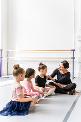 Woman with little ballerinas in cute skirt during ballet training in studio