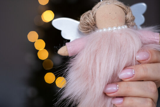 Beautician holding christmas angel ornament showing delicate nail art design
