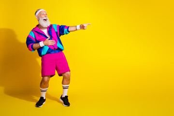 Full length photo of cheerful positive mature guy dressed retro sport jacket pointing finger emtpy...