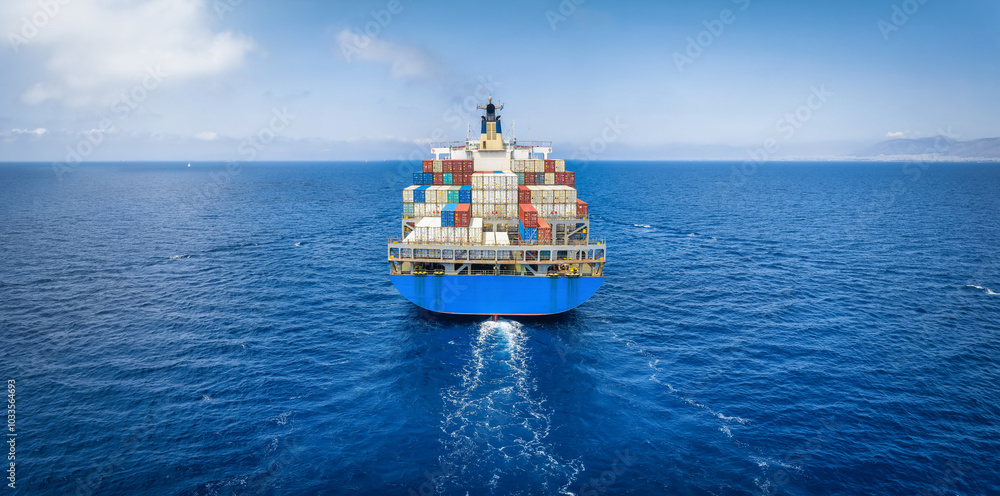 Wall mural rear view of a large container cargo ship traveling over the ocean with copy space