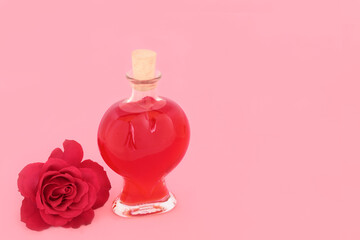 Rose flower and heart shape perfume bottle. Romantic Valentines day or birthday gift on pink background. Romantic love concept.