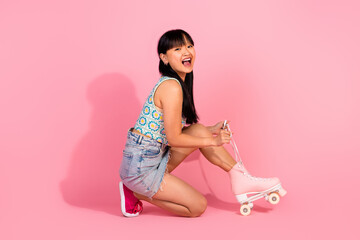 Photo of good mood cheerful girl wear stylish clothes riding skate rollers isolated on pink color...