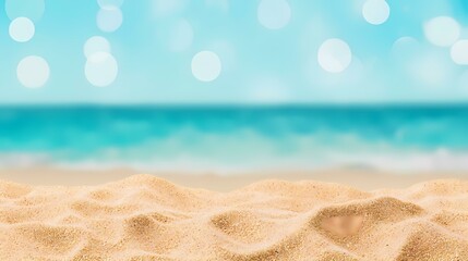 Obraz premium The image shows a close-up of soft, light tan sand with a blurred background of a turquoise ocean and a light blue sky.