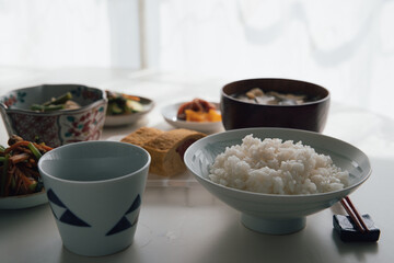 ヘルシーな日本の家庭料理の定食。ご飯・味噌汁・タラコのだし巻き・納豆・小鉢・漬物