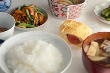 ヘルシーな日本の家庭料理の定食。ご飯・味噌汁・タラコのだし巻き・納豆・小鉢・漬物