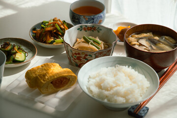 ヘルシーな日本の家庭料理の定食。ご飯・味噌汁・タラコのだし巻き・納豆・小鉢・漬物