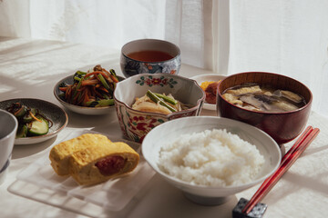 ヘルシーな日本の家庭料理の定食。ご飯・味噌汁・タラコのだし巻き・納豆・小鉢・漬物