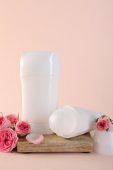 Different deodorants and beautiful rose flowers on beige background