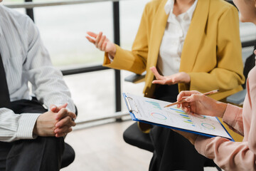 Strategic Discussion: A business team collaborates on a project, reviewing data and charts on a clipboard, their focused expressions convey serious engagement in the meeting. 