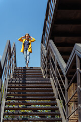Middle-aged woman descending an outdoor staircase with hands behind her head