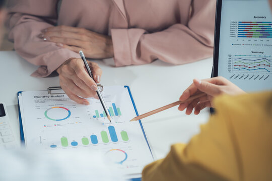 Data-Driven Decisions: A close-up of a business meeting, two hands point to graphs and charts, symbolizing the collaborative process of analyzing data and making informed decisions.  