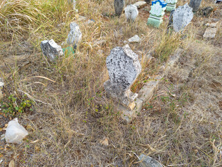 cemetery residential area, tombstones filled with dry grass. focus on the gravestone