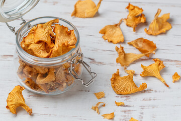 Dried chanterelles in a glass jar on a wooden table. Useful forest mushrooms. Cantharēllus cibārius. Selective focus